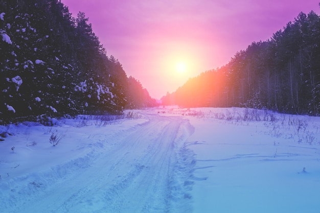 Wiejski zimowy krajobraz o wschodzie słońca. Wiejska droga pokryta śniegiem