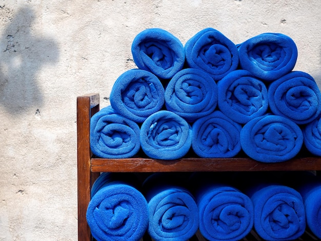 Wiele basenów z niebieskimi ręcznikami układa się na drewnianej półce dla gościa przy basenie w koncepcji wakacji w ośrodku hotelowym