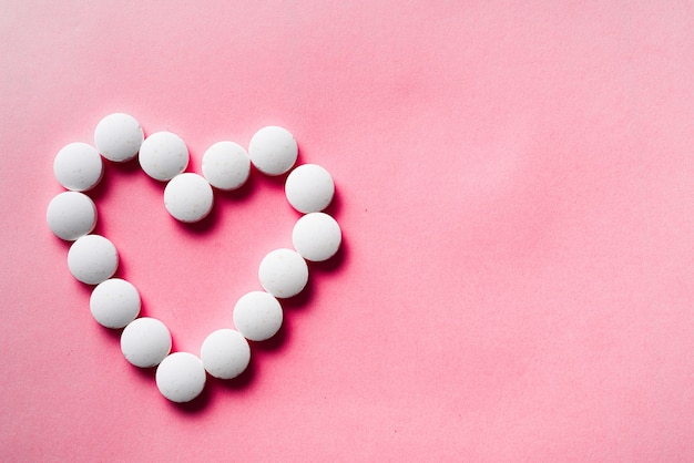 wiele białych tabletek z serca na różowym tle. zaakceptuj koncepcję prezentów. Koncepcja kardiologii lub miłości