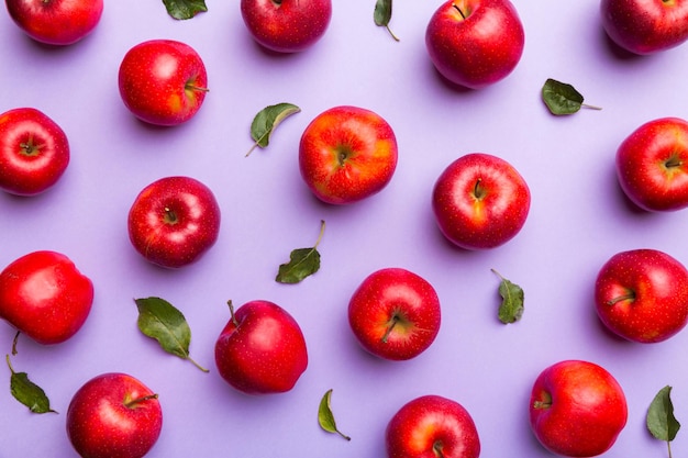 Wiele czerwonych jabłek na kolorowym tle, widok z góry. Jesienny wzór ze świeżym jabłkiem nad widokiem