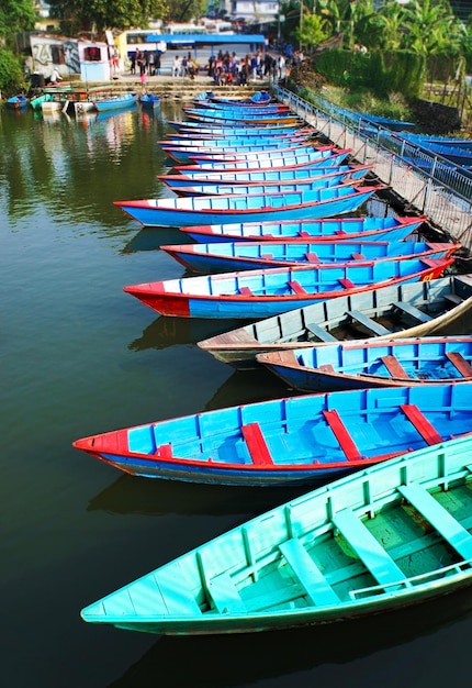 Wiele drewnianych niebieskich i zielonych łodzi na stacji nad jeziorem w Pokhara Nepal