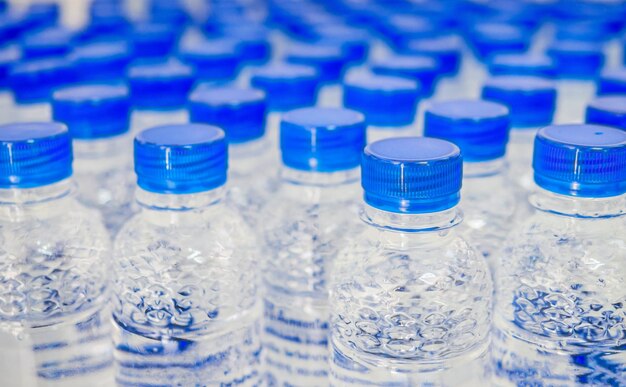 Zdjęcie wiele niebieskich czapek na butelki z wodą pitną i czyste butelki wody pitnej w wodzie pitnej