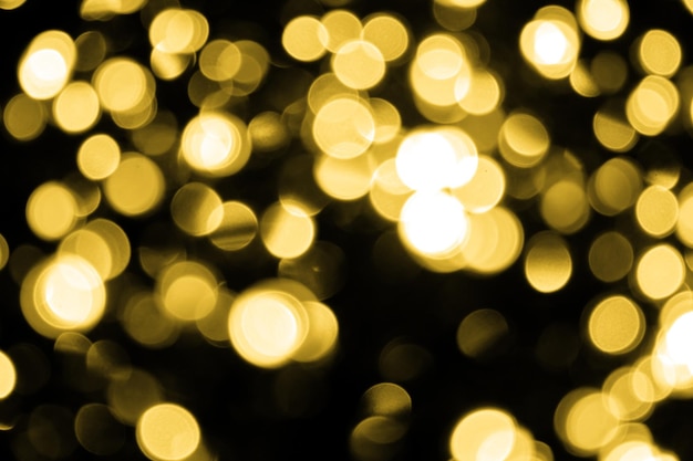 Wiele nieostrych świątecznych złotych lampek bokeh na czarnym tle Niewyraźne abstrakcyjne tekstury złotego brokatu