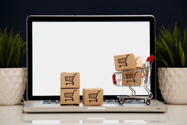 Wiele pudełek papierowych w małym koszyku na zakupy na klawiaturze laptopa koncepcje dotyczące zakupów online, że konsumenci mogą kupować rzeczy bezpośrednio z domu lub biura za pomocą kilku kliknięć w przeglądarce internetowej
