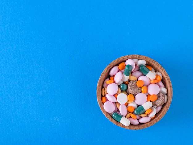 Wiele różnych kolorowych tabletek w drewnianej misce