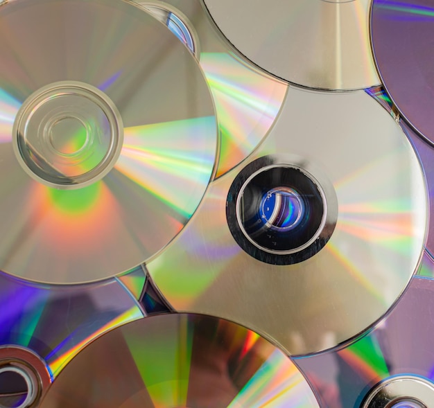 Wiele starych płyt CD reprezentuje technologię z lat dziewięćdziesiątych stosy płyt CD starych piosenek i starych filmów, które były używane wcześniej i umieszczone na białym stole zbliżenie selektywne skupienie