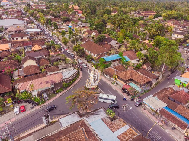 Wiele willi z brązowo-pomarańczowym dachem gontowym pomiędzy tropikalnymi drzewami na tle nieba w Ubud na Bali Słońce świeci na nich Poziome zdjęcie z lotu ptaka