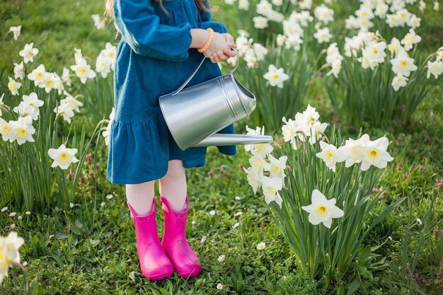 Wielkanoc Cute little girl 5 lat z uszami królika podlewa daffodils na trawniku Happy child Wakacje wiosenne