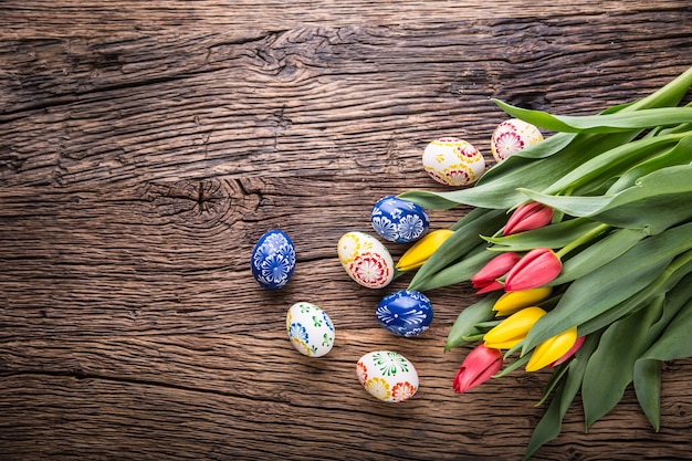 Zdjęcie wielkanoc. ręcznie robione pisanki i tulipany wiosna na starym drewnianym stole.