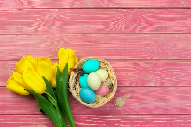 Wielkanoc, święta, tradycja i przedmiot - zbliżenie kolorowych jaj i kwiatów tulipanów na drewniane deski