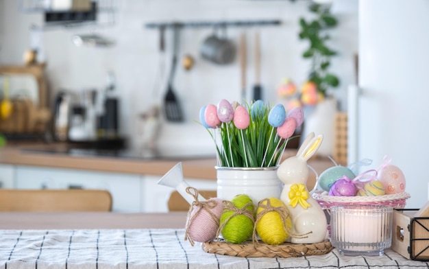 Wielkanocna dekoracja kolorowych jaj w koszu i królika na kuchennym stole w stylu rustykalnym Świąteczne wnętrze wiejskiego domu