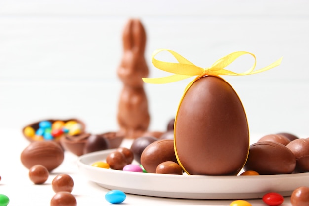 Wielkanocna kompozycja z czekoladowymi jajkami i czekoladowym królikiem na drewnianym tle