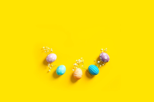 Wielkanocna płaska kompozycja z kolorowymi malowanymi naturalnymi jajkami i kwiatami