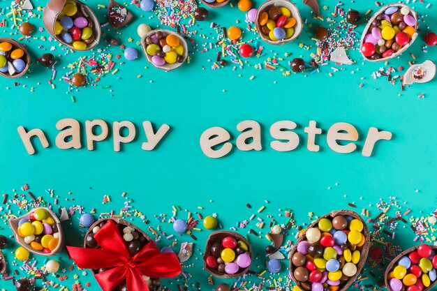 Wielkanocna ramka z czekoladowymi jajkami i słodyczami na różowym tle. Wesołych Świąt tekst. Widok z góry, układ płaski