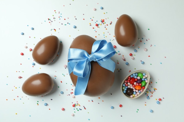 Wielkanocne jajka czekoladowe, cukierki i posypka na białym tle