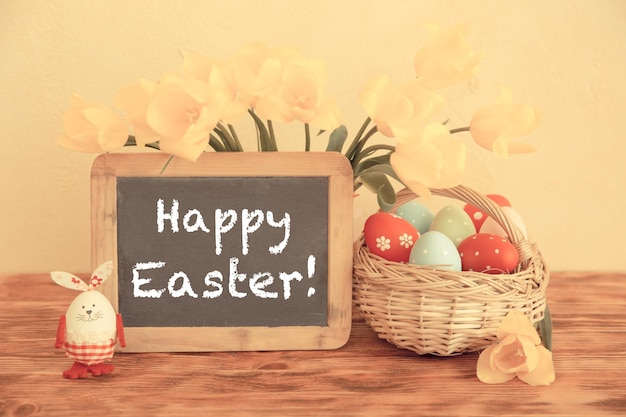 Wielkanocne jajka kwiaty i tablica pusta na drewnianym stole Koncepcja wiosennych wakacji