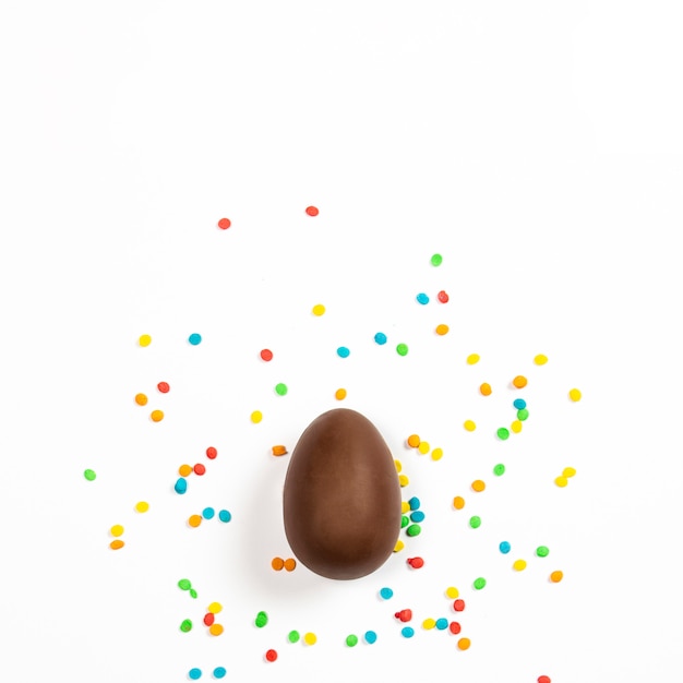 Wielkanocne jajko czekoladowe i kolorowe dekoracje na lekkiej powierzchni. Wielkanocny pojęcie, wielkanocne smakołyki. Plac. Leżał płasko, widok z góry