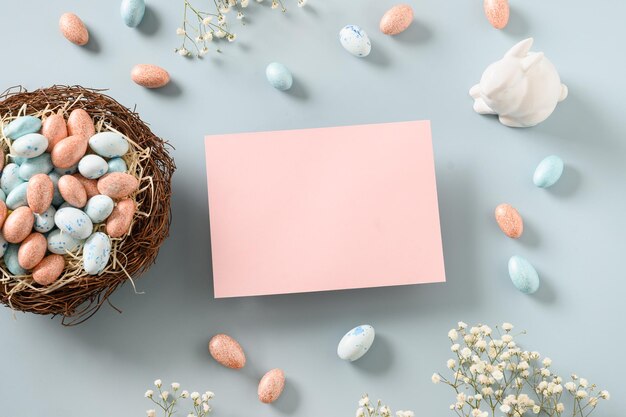Wielkanocne puste miejsce na pozdrowienia z pastelowymi czekoladowymi słodyczami jako gniazdo jaj i króliczek