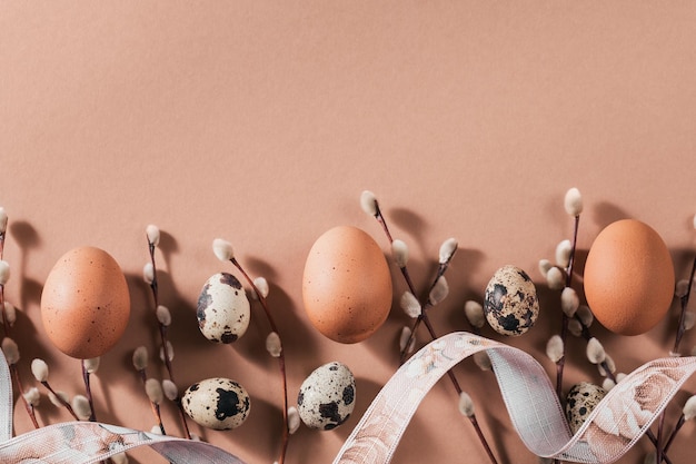 Wielkanocne tło z naturalnymi kolorowymi jajkami i brązowymi piórami