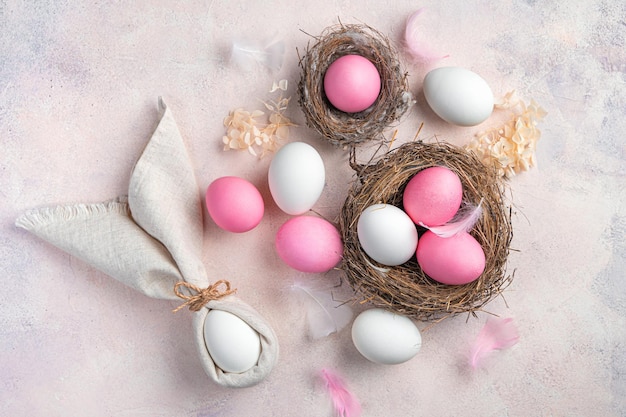 Wielkanocne tło z różowymi i białymi jajkami i zajączek z serwetki na jasnoróżowym tle Koncepcja Wesołych Świąt