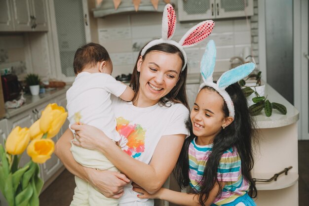 Wielkanocne tradycje rodzinne Kochająca młoda mama uczy dzieci malowania jajek na Wielkanoc, siedząc razem przy kuchennym stole