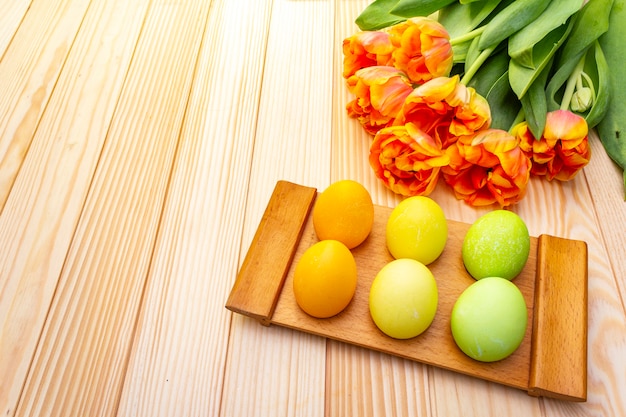 Wielkanocni jajka i pomarańczowy tulipan kwitną na drewnianym stole