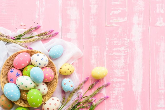 Wielkanocni jajka w gniazdeczku z kwiatem na pastelowych menchii i bielu drewnianym tle.