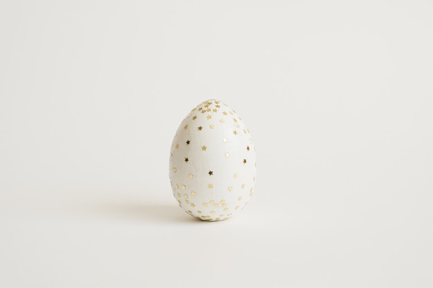 Wielkanocny biały jajko z błyskotliwość gwiazdami odizolowywać na białym tle
