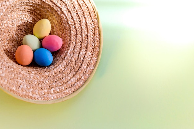 Wielkanocny obrazek z kolorowymi jajkami w słomkowym kapeluszu w wiejskim stylu