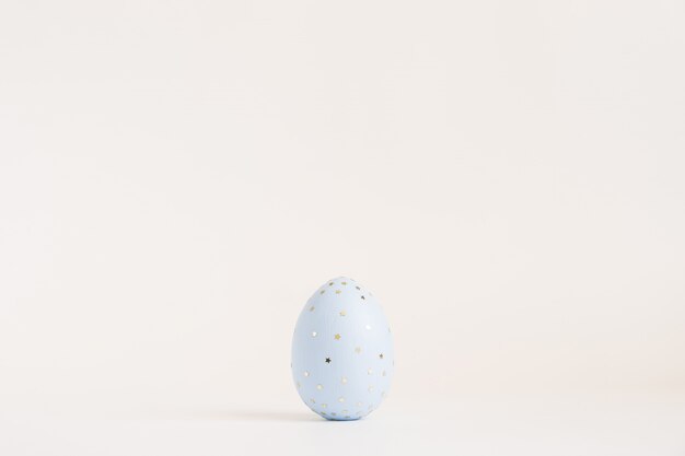 Wielkanocny złoty dekorujący jajko z błyskotliwość gwiazdami odizolowywać na biel powierzchni.