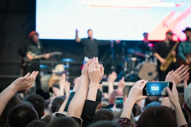 Wielki koncert uliczny na świeżym powietrzu tłum ludzi wita swoich ulubionych muzyków i robi zdjęcia smartfonem