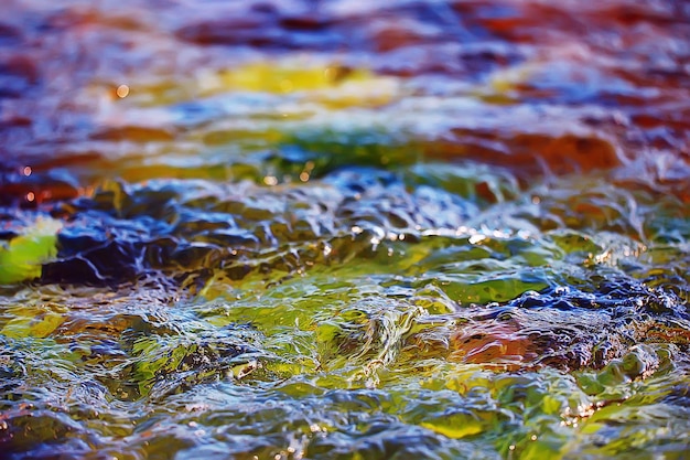 wielobarwna faktura tafli strumienia wody, czysta woda, kolorowe kamienie na dnie rzeki
