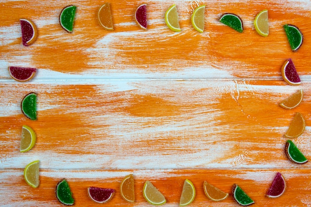 Wielobarwna marmolada w formie plasterków cytrusowych ułożonych jako rama na pomarańczowej desce