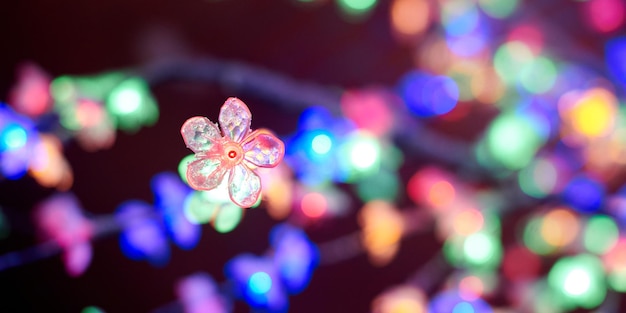 Wielobarwne światła bokeh z dekoracyjnych girland świecących kwiatów na wakacyjnych wielobarwnych światłach