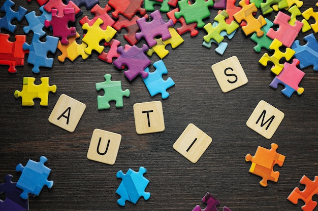 Zdjęcie wielobarwny puzzli z napisem autyzm na czarnym tle koncepcja światowego dnia autyzmu