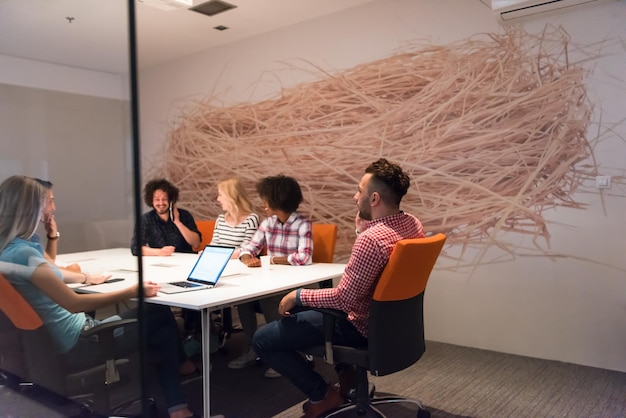 Wieloetniczny startupowy zespół biznesowy na spotkaniu w nowoczesnym, jasnym wnętrzu biurowym, burza mózgów, pracujący na laptopie i tablecie