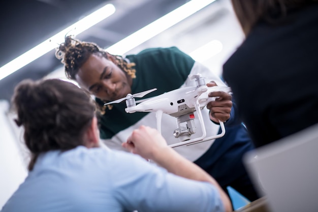 wieloetniczny startupowy zespół biznesowy omawiający nowy biznesplan, pracujący na laptopie i tablecie podczas nauki o technologii dronów dla rozwoju nowego biznesu