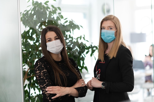 wieloetniczny zespół biznesmenów pracujący w jasnym, nowoczesnym biurze noszący ochronną maskę medyczną podczas wybuchu koronawirusa nowa normalna koncepcja w biznesie