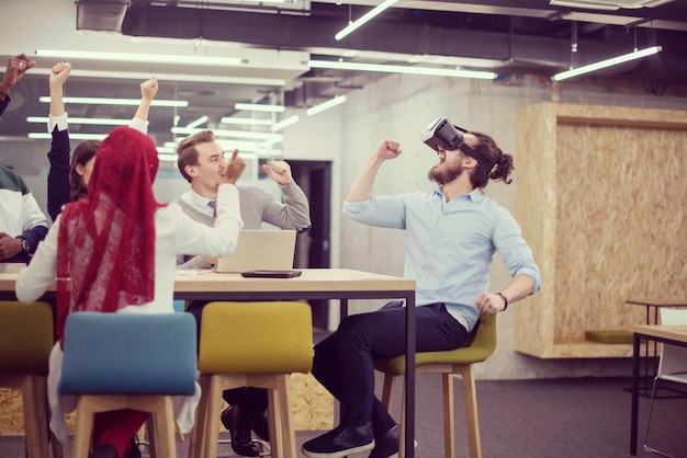 Wieloetniczny zespół biznesowy korzystający z zestawu słuchawkowego wirtualnej rzeczywistości na spotkaniu biurowym Spotkanie programistów z symulatorem wirtualnej rzeczywistości przy stole w kreatywnym biurze.