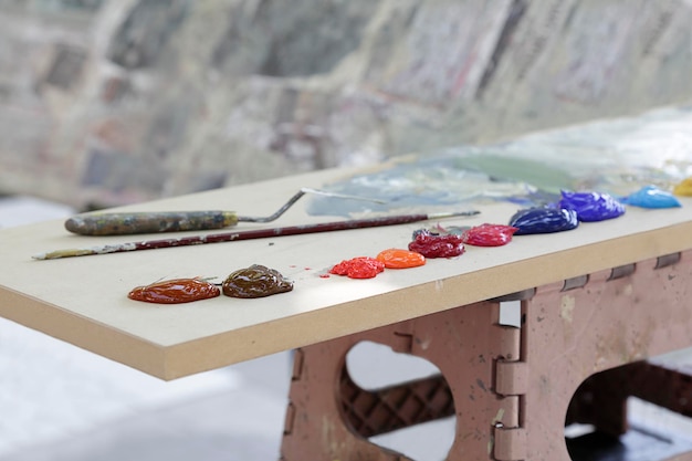 Wielokolorowa farba olejna, artystyczny pędzel i szpachelka nad drewnianym stołem