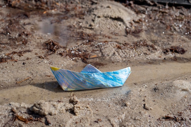 Wielokolorowa papierowa łódź origami w strumieniu lub kałuży Symbol dzieciństwa lub kawałek światła w ciemnym świecie