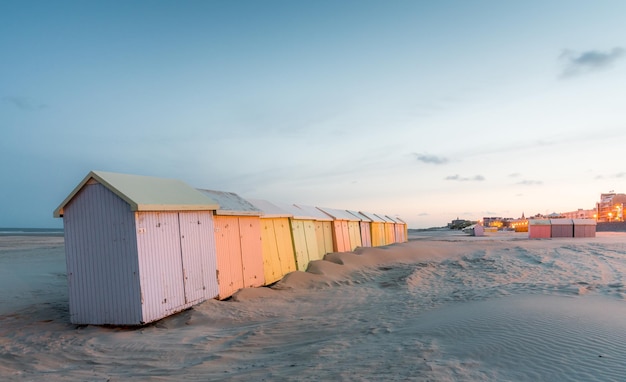 Wielokolorowe kabiny kąpielowe ustawione w kolejce na bezludnej plaży BerckPlage wczesnym rankiem