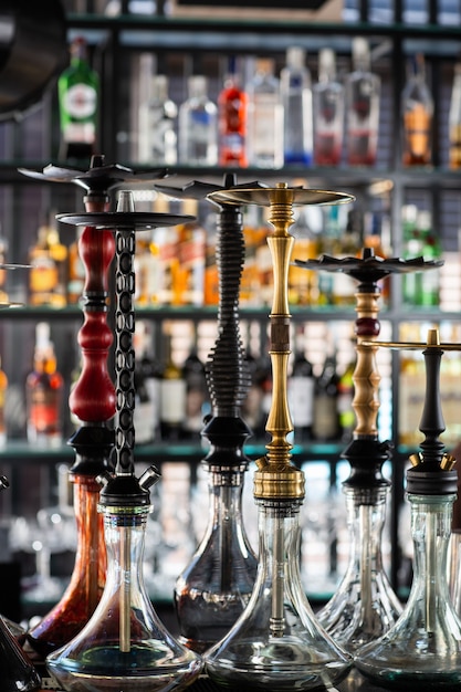 Wielokolorowe piękne fajki wodne stoją na stole na tle alkoholu przy barze