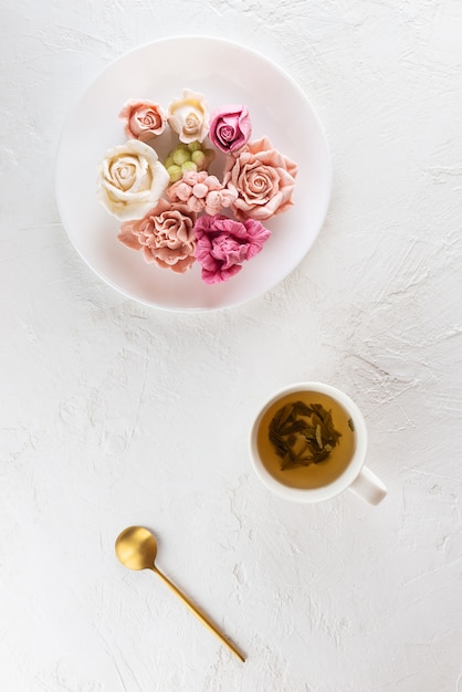 Wielokolorowy zefir w formie kwiatów na talerzu z filiżanką zielonej herbaty