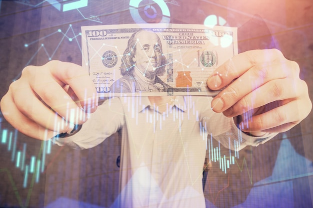 Wielokrotna ekspozycja hologramu wykresu forex i banknotów dolarów amerykańskich oraz rąk człowieka Koncepcja analizy technicznej
