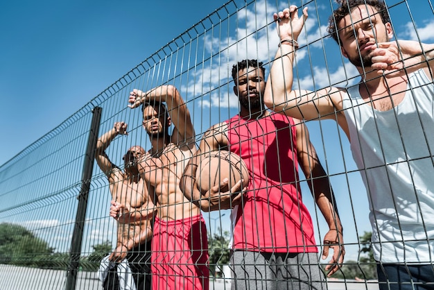 Wielokulturowa grupa koszykarzy stojących w pobliżu siatki na korcie