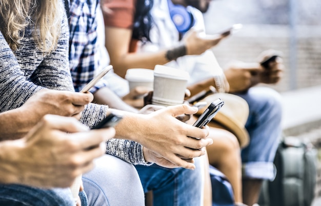 Wielokulturowa grupa przyjaciół używająca smartfona z kawą podczas przerwy na studia college