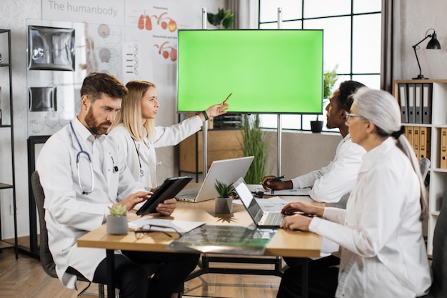 Wielokulturowi lekarze używający monitora z zielonym ekranem