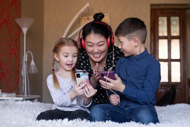 Wielonarodowa mama rodzinna i dzieci patrzą na telefon, bawiąc się słuchając muzyki