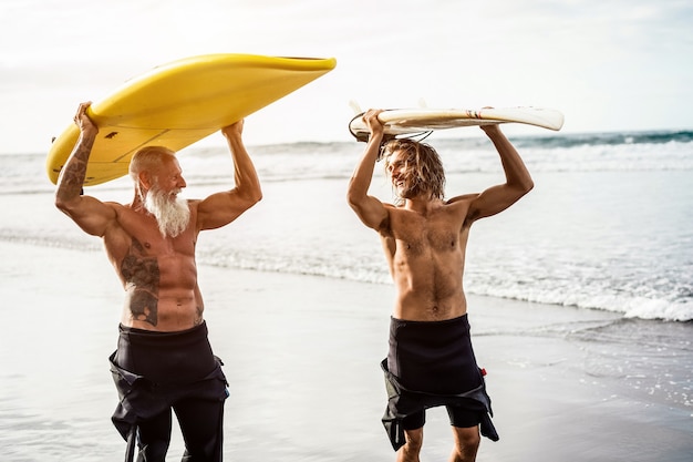 Wielopokoleniowi Przyjaciele Surfują Na Tropikalnej Plaży - Rodzinni Ludzie Dobrze Się Bawią, Uprawiając Sporty Ekstremalne - Radosna Starsza Osoba I Koncepcja Zdrowego Stylu życia - Główny Nacisk Na Starszą Twarz